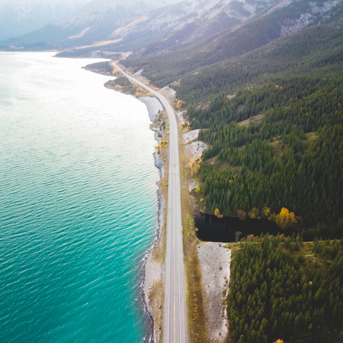 Highway along a turquoise lake in the Rockies